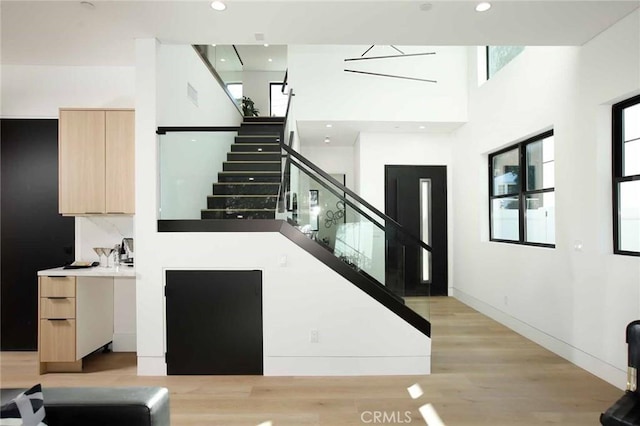 staircase featuring recessed lighting, baseboards, a towering ceiling, and wood finished floors