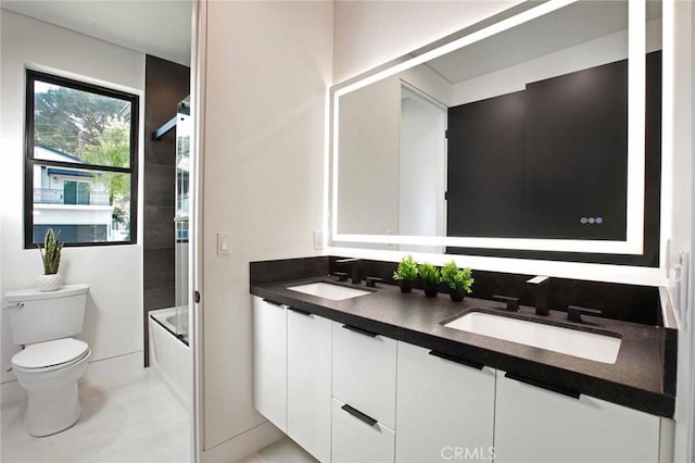 bathroom with double vanity, toilet, shower / bathtub combination, and a sink