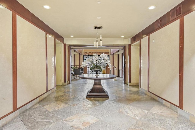 corridor with stone tile floors, recessed lighting, visible vents, and baseboards