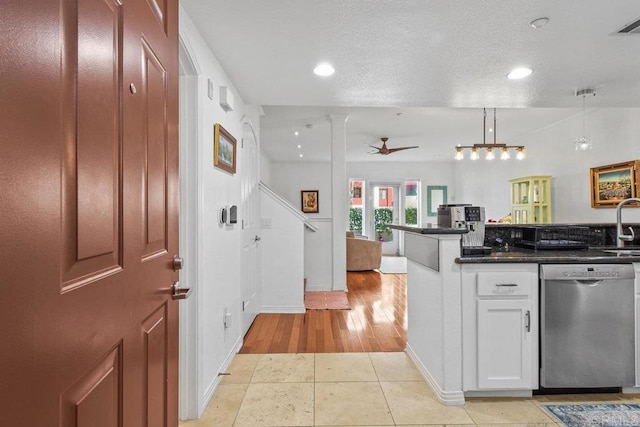 kitchen featuring a ceiling fan, stainless steel dishwasher, dark countertops, a textured ceiling, and light tile patterned flooring