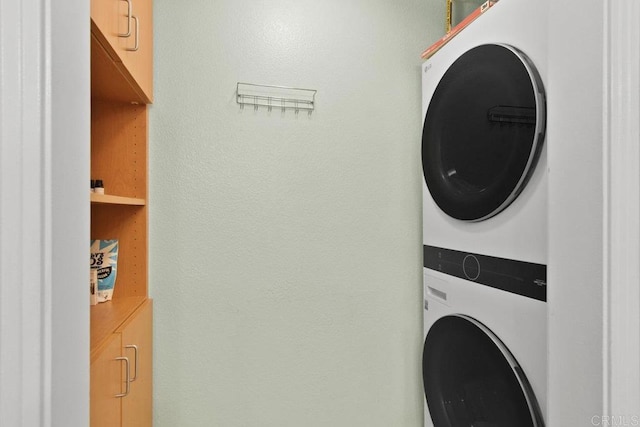 washroom with cabinet space and stacked washer / dryer