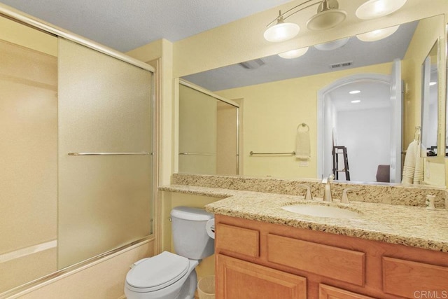 bathroom featuring shower / bath combination with glass door, visible vents, toilet, and vanity