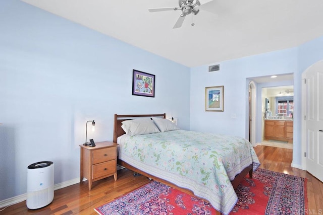 bedroom featuring a ceiling fan, wood finished floors, visible vents, and baseboards