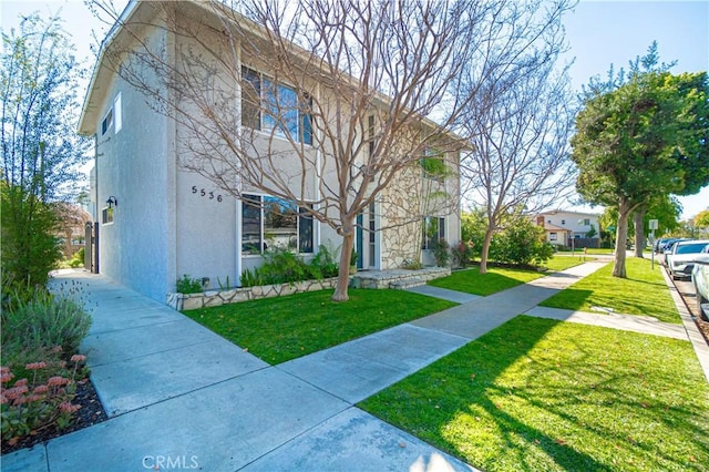 view of front of home featuring stucco siding and a front lawn