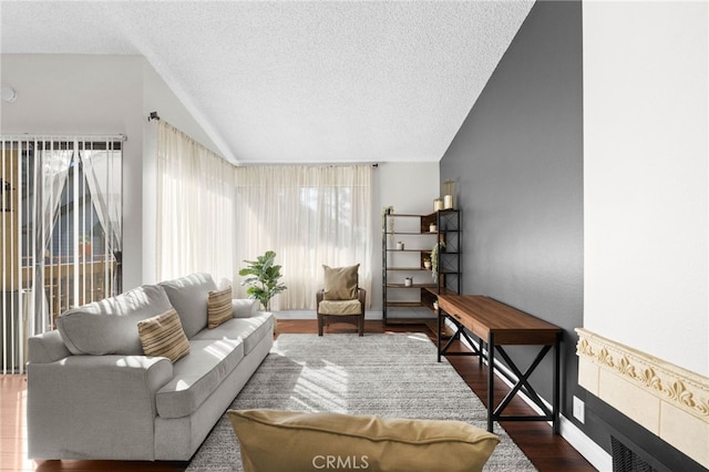 living room featuring a textured ceiling, wood finished floors, a fireplace, baseboards, and vaulted ceiling