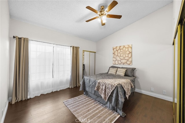 bedroom with a ceiling fan, a textured ceiling, wood finished floors, baseboards, and vaulted ceiling