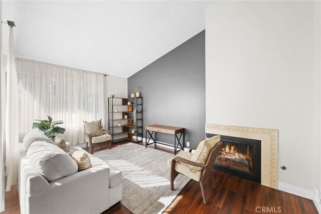 living area with lofted ceiling, wood finished floors, baseboards, and a tile fireplace