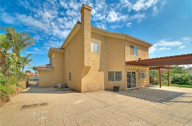 rear view of house featuring stucco siding, a pergola, a tile roof, a patio, and fence