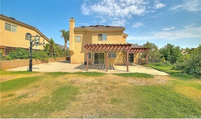 rear view of house featuring stucco siding, a pergola, a lawn, and a patio