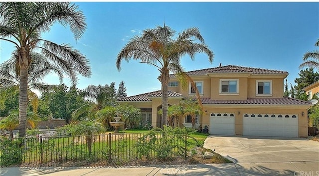 mediterranean / spanish house with stucco siding, driveway, fence, an attached garage, and a tiled roof