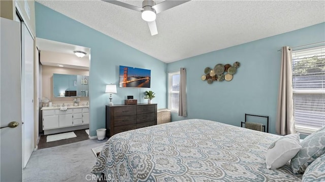 bedroom featuring connected bathroom, vaulted ceiling, carpet flooring, a textured ceiling, and a ceiling fan