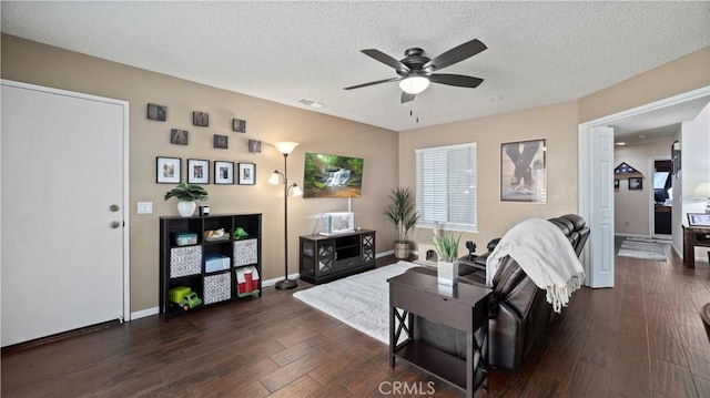 living area featuring dark wood finished floors, visible vents, a textured ceiling, and a ceiling fan