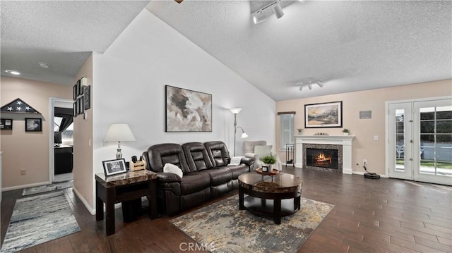 living area with a glass covered fireplace, a textured ceiling, track lighting, and dark wood-style flooring