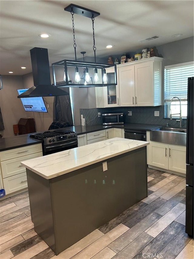 kitchen featuring visible vents, black appliances, a sink, island range hood, and wood tiled floor