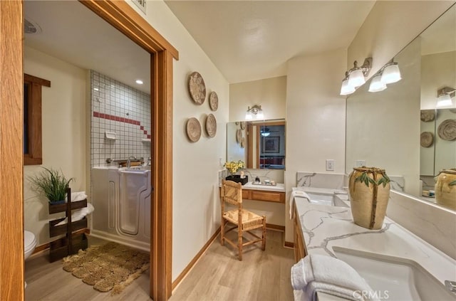 bathroom featuring double vanity, baseboards, and wood finished floors