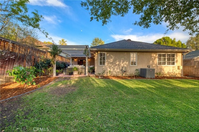 back of property with a shingled roof, stucco siding, cooling unit, a yard, and a fenced backyard