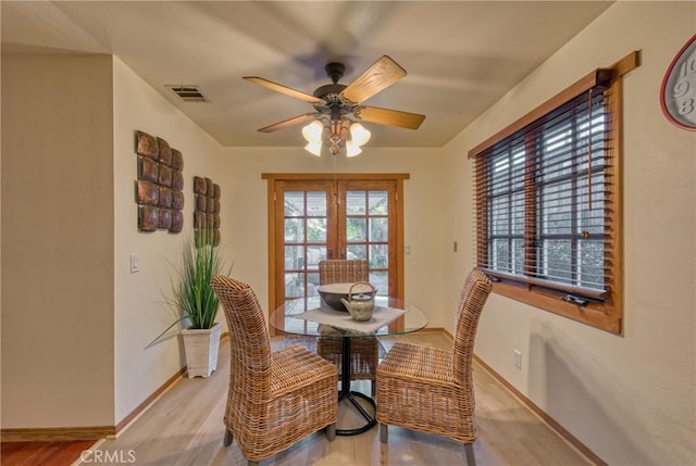 dining room featuring light wood-style floors, baseboards, visible vents, and ceiling fan