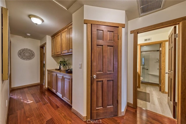 hall featuring dark wood finished floors, visible vents, and baseboards