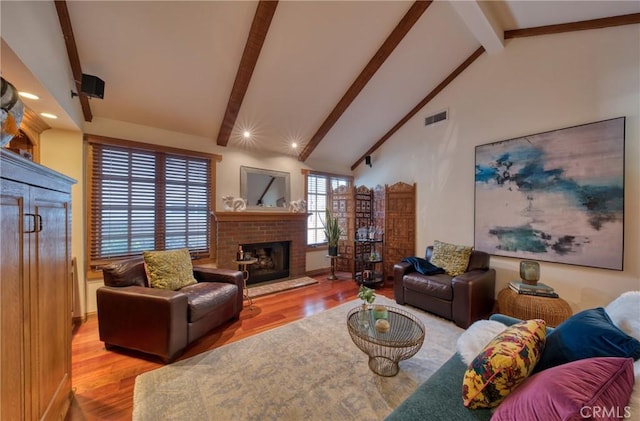 living area featuring visible vents, beam ceiling, high vaulted ceiling, wood finished floors, and a fireplace