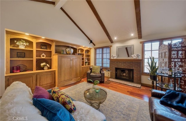 living area with beam ceiling, a fireplace, high vaulted ceiling, and wood finished floors