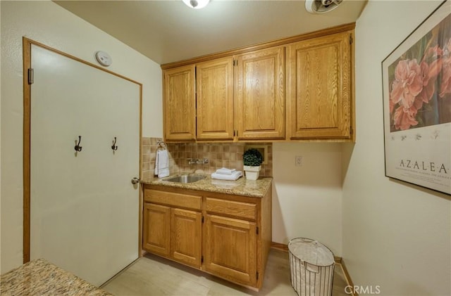 kitchen featuring brown cabinetry, tasteful backsplash, and a sink