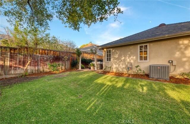 view of yard featuring central AC unit and fence