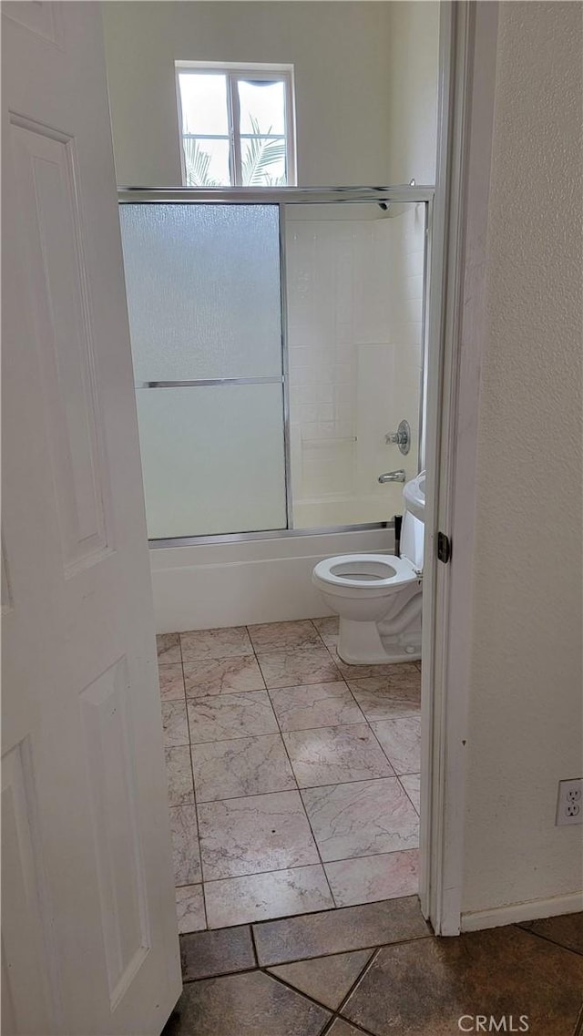 bathroom featuring combined bath / shower with glass door and toilet