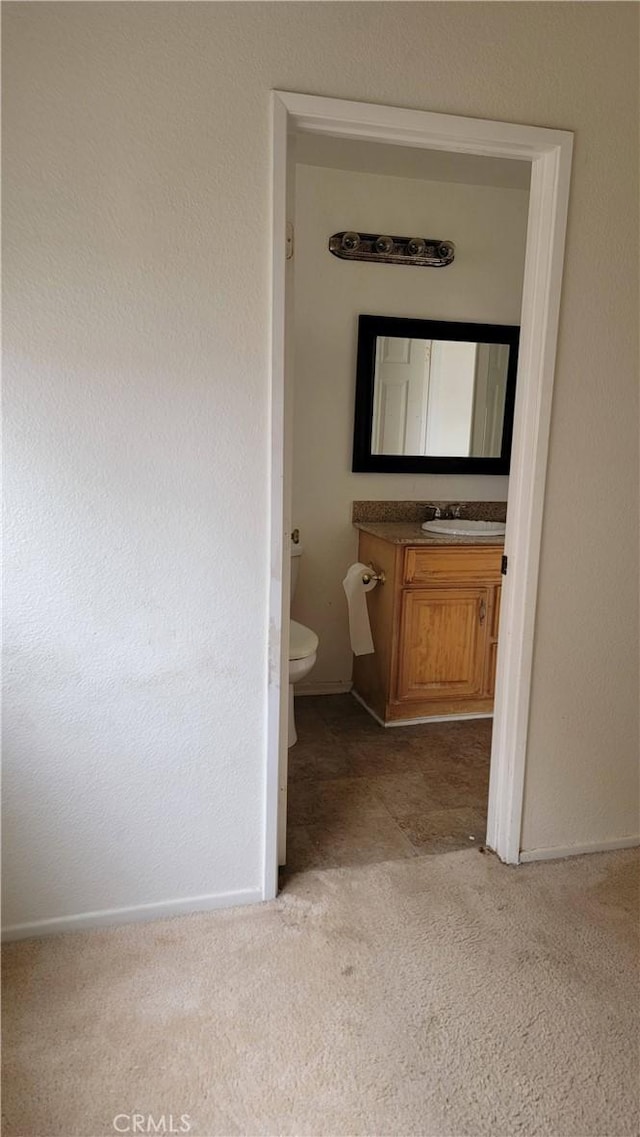 bathroom featuring vanity, toilet, and baseboards