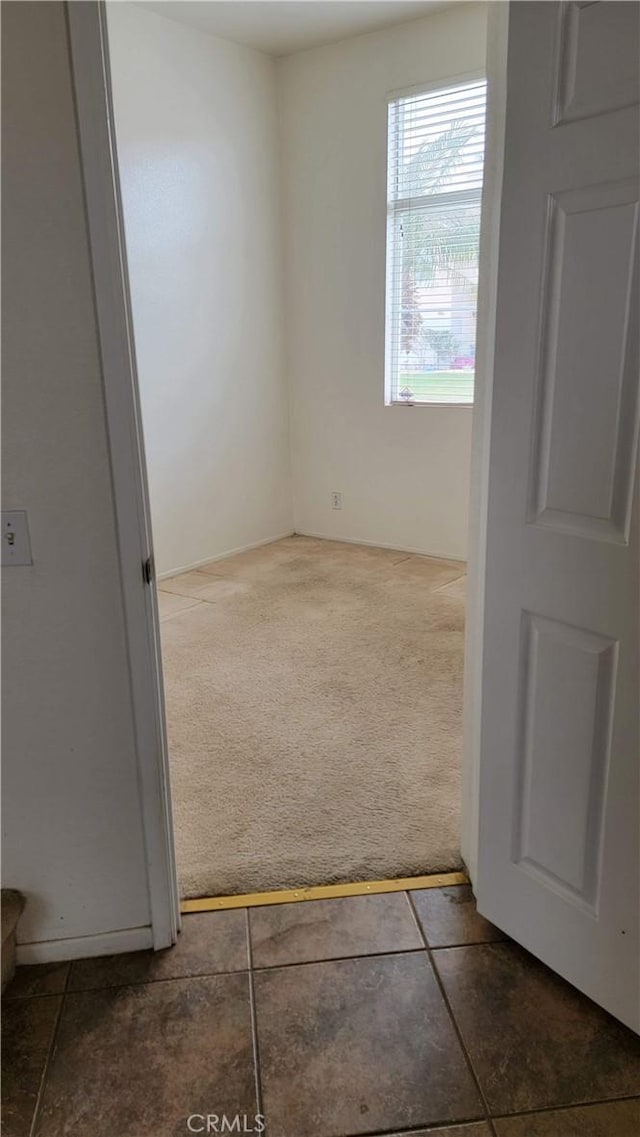 spare room featuring dark tile patterned floors and dark carpet