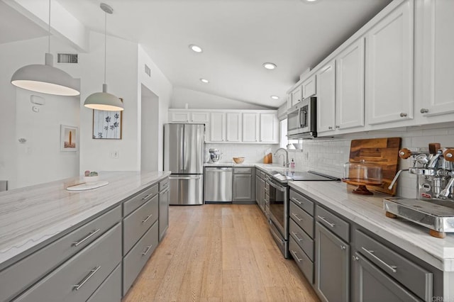 kitchen featuring visible vents, gray cabinetry, appliances with stainless steel finishes, decorative backsplash, and lofted ceiling