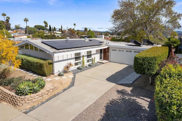 view of front of home featuring solar panels, concrete driveway, and a garage