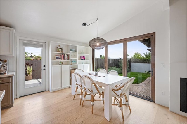 dining room featuring vaulted ceiling and light wood-style floors