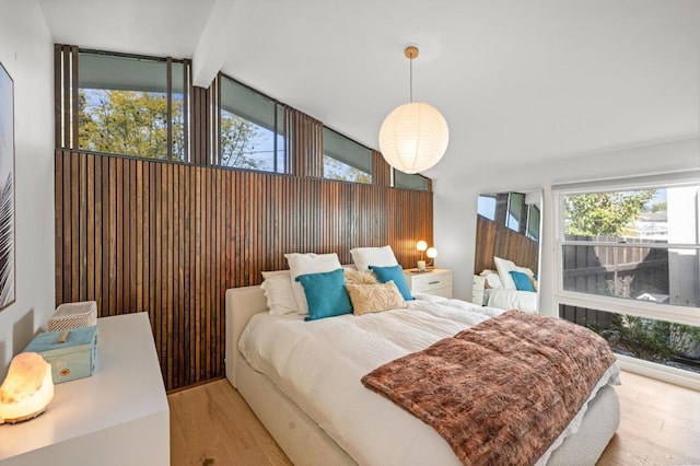 bedroom featuring multiple windows, lofted ceiling with beams, and wood finished floors