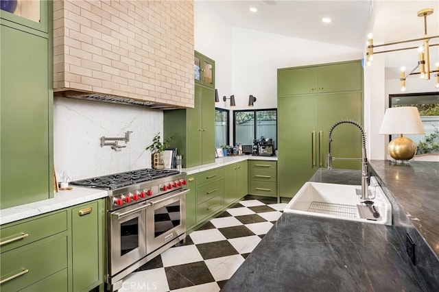 kitchen featuring double oven range, green cabinetry, a sink, decorative backsplash, and dark floors