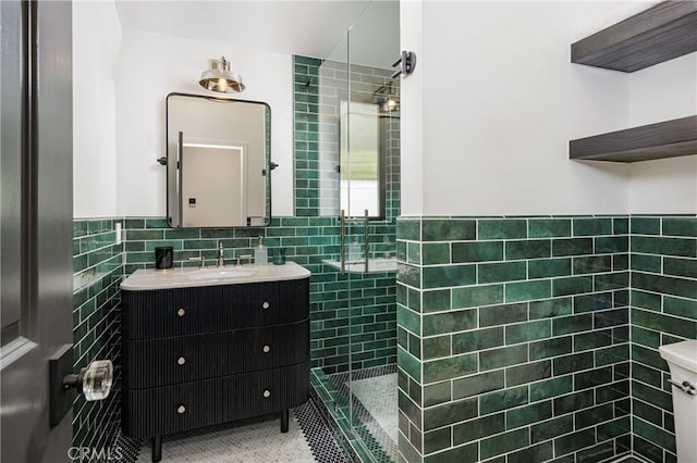 full bathroom featuring a wainscoted wall, tile walls, tile patterned flooring, tiled shower, and vanity