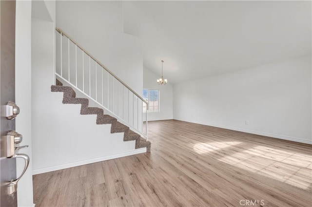 foyer with wood finished floors, baseboards, high vaulted ceiling, stairs, and a chandelier