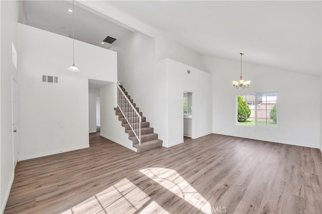 unfurnished living room with a chandelier, stairway, visible vents, and wood finished floors