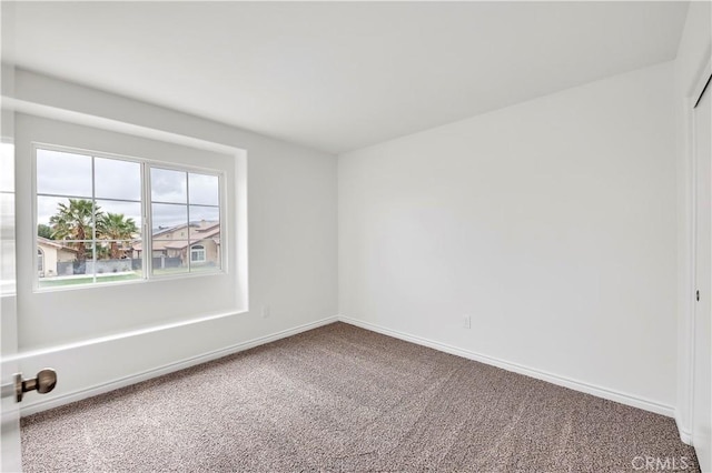 unfurnished room with baseboards and carpet floors