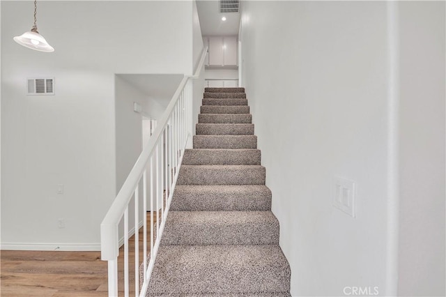 stairway with visible vents, baseboards, and wood finished floors