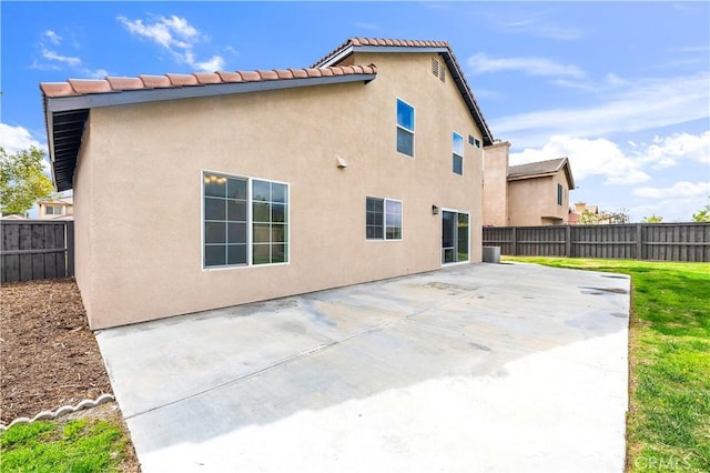 rear view of property featuring stucco siding, a fenced backyard, and a patio area