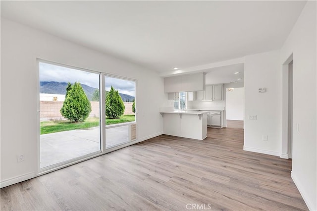 unfurnished living room featuring recessed lighting, a mountain view, baseboards, and light wood-style floors