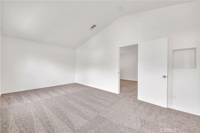 carpeted spare room featuring lofted ceiling, baseboards, and visible vents