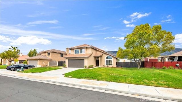 view of front of property with a front yard, fence, driveway, an attached garage, and stucco siding