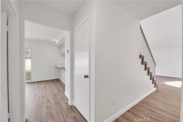 corridor with stairway, baseboards, and wood finished floors