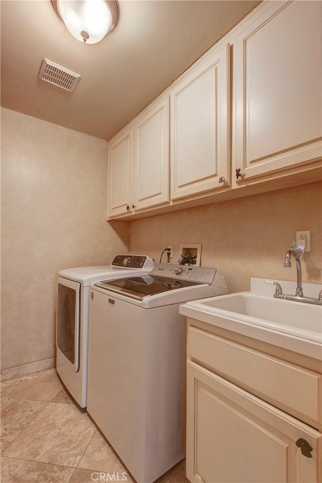 clothes washing area with cabinet space, visible vents, washer and dryer, and a sink