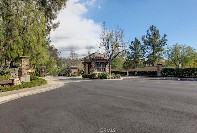 view of street featuring sidewalks, curbs, and a gated entry