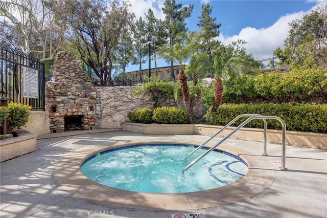 view of pool featuring an outdoor stone fireplace and a hot tub