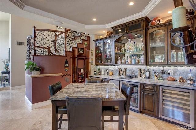 dining room with visible vents, beverage cooler, indoor wet bar, and crown molding