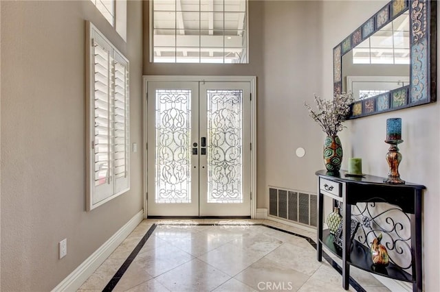 foyer entrance with visible vents, french doors, a high ceiling, and baseboards