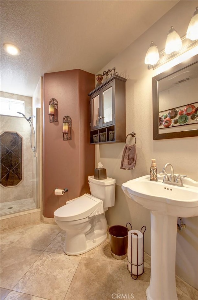 bathroom with a shower stall, toilet, tile patterned floors, a textured ceiling, and a sink